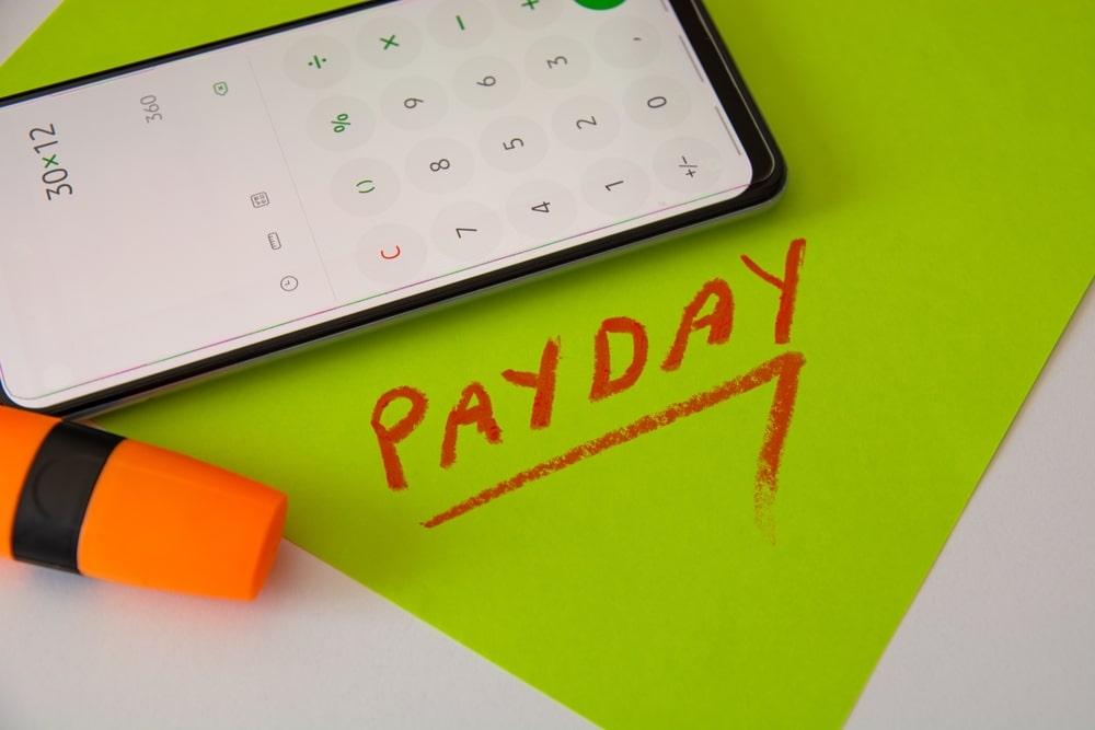 Payday Title Written Next To A Phone With Calculator Open