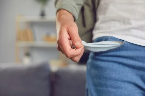 young man in casual shirt looking downward with hand covering face