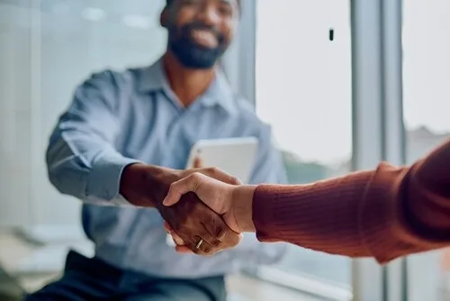 two business professionals shaking hands in modern office setting